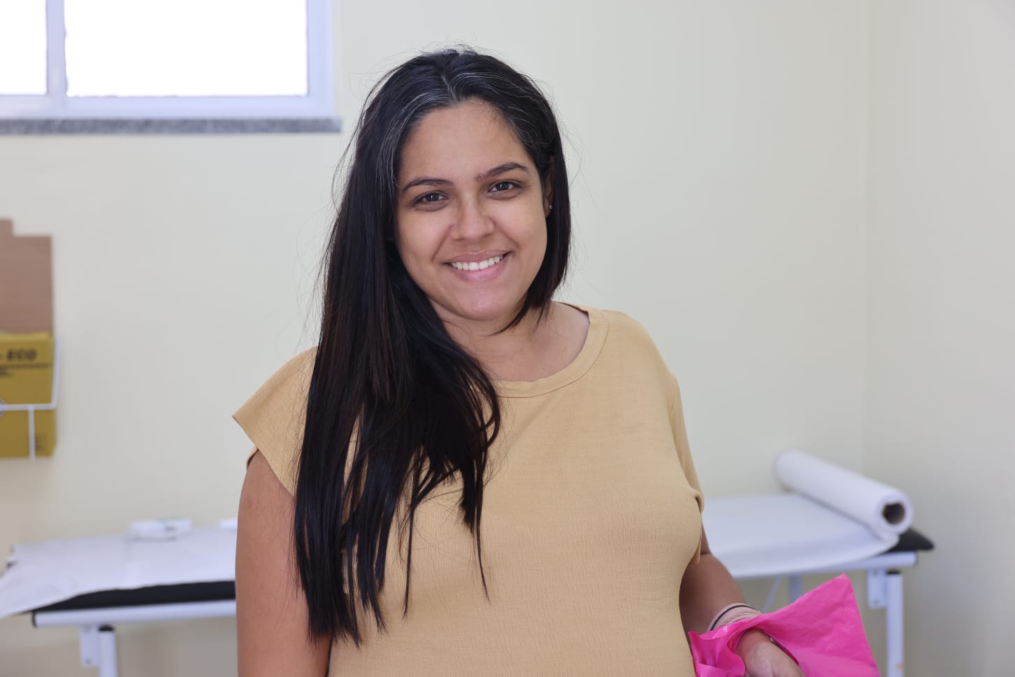 Jessika Oliveira posa para a foto; ela é mulher cis, de cabelo preto e liso; e veste uma blusa bege